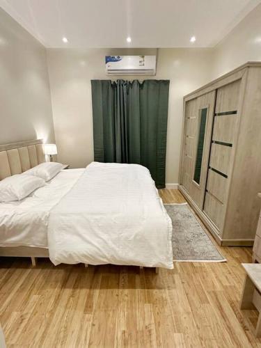 106 A شقة جميلة بغرفتين نوم ودخول ذاتي في الرياض: غرفة نوم بسرير ابيض كبير وستائر خضراء