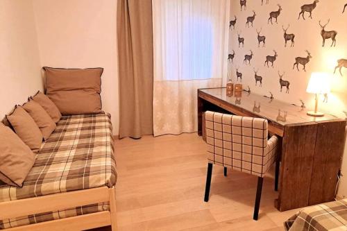 een woonkamer met een bureau en een tafel met een stoel bij Comfortable apartment near the ski station with parking in Laax