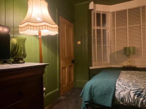 a bedroom with green walls and a bed with a lamp at Petite Jessamine in St Margarets at Cliff