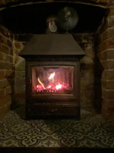 a brick fireplace with a fire in it at Petite Jessamine in St Margarets at Cliff