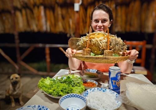 uma mulher segurando um cesto de comida em uma mesa em Sông Mê Home em Vinh Long