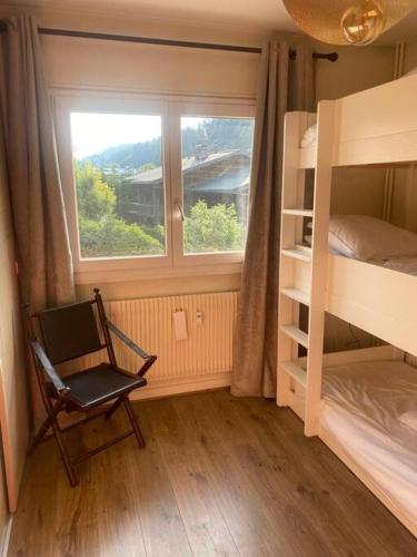 - une chambre avec une fenêtre, une chaise et des lits superposés dans l'établissement Appartement Au pied du Jaillet, à Megève
