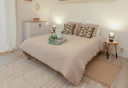 een witte slaapkamer met een groot bed met kussens bij Appartement - L'ESCALE DE MONTMOROT - CALME & SÉRÉNITÉ in Montmorot