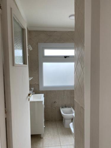 a bathroom with a window and a sink and a toilet at Departamento centrico in Ushuaia
