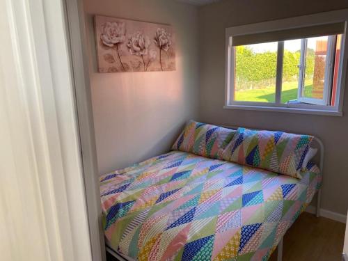 a bedroom with a bed and a window at The Chalet in Stalham