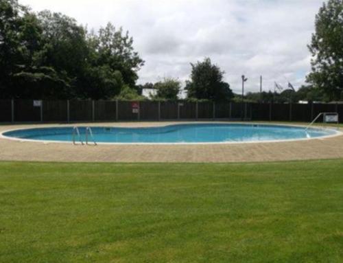 an empty swimming pool in a park with grass at The Chalet in Stalham