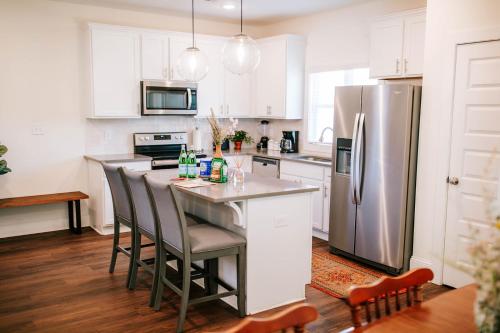 a kitchen with white cabinets and a stainless steel refrigerator at Bright Artist's Cottage-Mins to Downtown, Campus in Athens