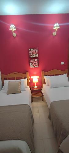 a room with two beds and a red wall at Volcán de Sal in Mazo
