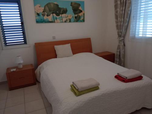 a bedroom with a white bed with two towels on it at 1 bedroom in Regina Gardes 2 in Paphos City