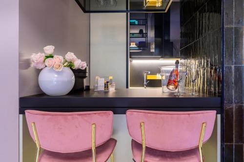 zwei rosa Stühle vor einer Theke mit einer Vase mit Blumen in der Unterkunft Boutique suite Rome in Rom