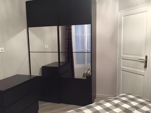 een slaapkamer met een zwarte dressoir en een spiegel bij Appartement moderne au centre de Paris, 3ème in Parijs