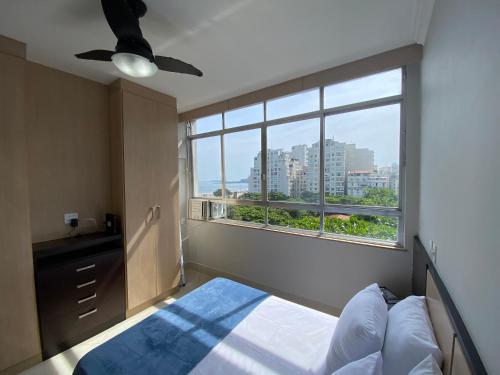 a bedroom with a bed and a large window at Loft Praia de Copacabana in Rio de Janeiro