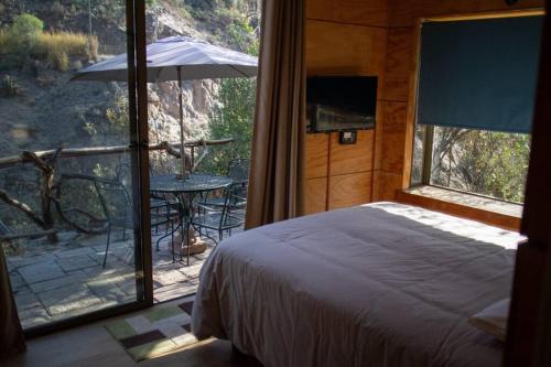 a bedroom with a bed and a balcony with an umbrella at Casa Ñilhue, Camino a la Farellones in Santiago
