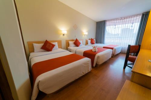 a hotel room with three beds and a window at Lake Titicaca Hotel in Puno