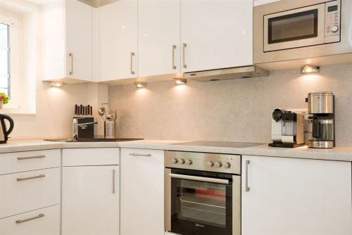 a kitchen with white cabinets and an oven at Haus-Seestern in Tinnum