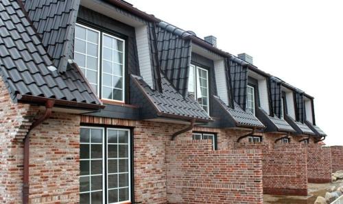 a brick house with black roofs and windows at Haus-Seestern in Tinnum