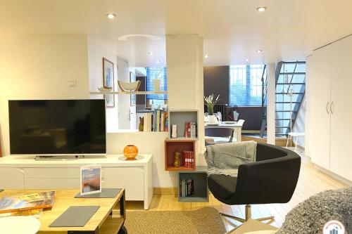 a living room with a television and a chair and a table at Loft de l'Artiste - Parking - Standing in Rouen