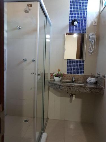 a bathroom with a glass shower and a sink at Hotel Minastur in Capitólio
