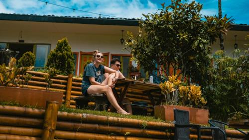 two people sitting on a fence in a garden at Viajero Salento Hostel in Salento