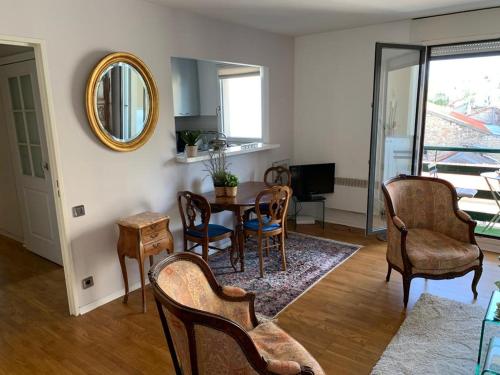 ein Wohnzimmer mit einem Tisch, Stühlen und einem Spiegel in der Unterkunft PARIS 10 ' BASTILLE (CHARENTON LE PONT) in Charenton-le-Pont