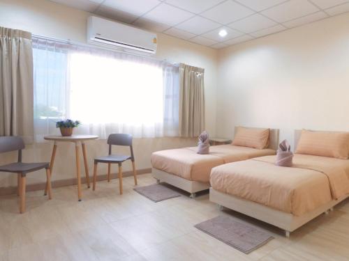a bedroom with two beds and a table and a window at Studio 36 in Bangkok