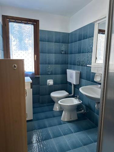 a blue tiled bathroom with a toilet and a sink at Maison Moioli - Appartamento 3 in Piamprato