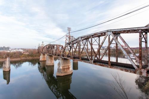 a train bridge over a river with reflections in the water at River View, Central, Elevator, Private Parking in Nashville