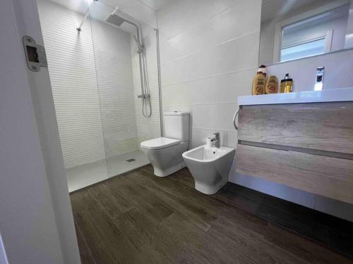 a white bathroom with a toilet and a shower at Apartamento Virgen del Mar in Almería