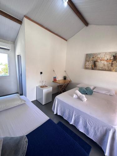 a room with two beds and a table with a window at Vila Cajuzinho in Caraíva