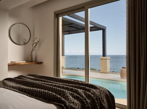 a bedroom with a swimming pool and a bed and a mirror at Seaside A Lifestyle Resort - Adults Only in Agia Pelagia