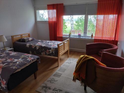 a bedroom with two beds and a chair and a window at saarnimaja in Hämeenlinna
