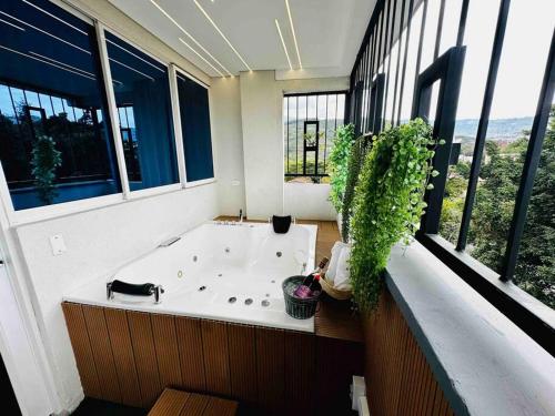 bañera en una habitación con ventanas grandes en noah apartasuite 601, en Cali