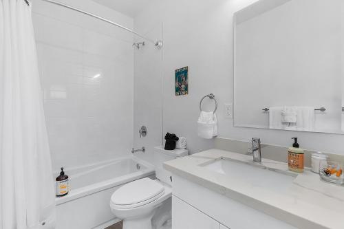 a white bathroom with a toilet and a sink at Tides of Seasmoke Suite in Seattle