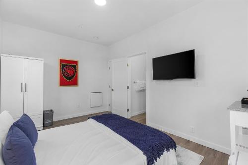 Tides of Seasmoke Suite في سياتل: غرفة نوم بيضاء مع سرير وتلفزيون بشاشة مسطحة