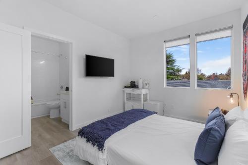 a white bedroom with a bed and a television at Tides of Seasmoke Suite in Seattle