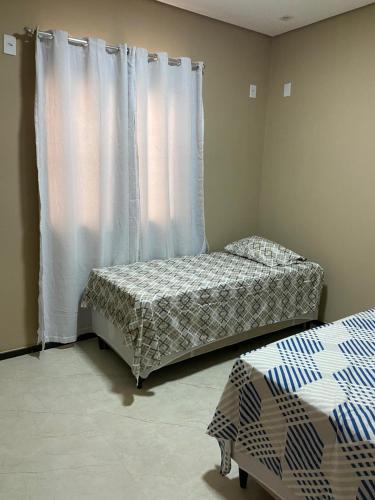 a bedroom with two beds and a window with curtains at CASA DE PRAIA in Prado