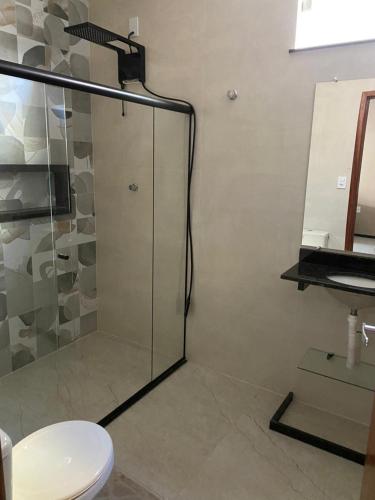 a bathroom with a glass shower with a toilet at CASA DE PRAIA in Prado