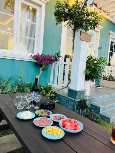 a wooden table with plates of fruit and wine glasses at Novaworld Phan thiết - Alina house- 2 bed rooms in Bình Sum