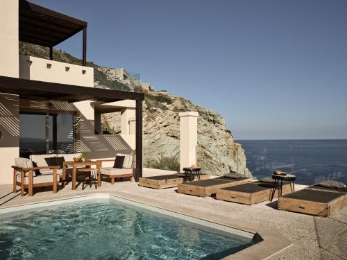 a villa with a swimming pool on a cliff at Seaside A Lifestyle Resort - Adults Only in Agia Pelagia