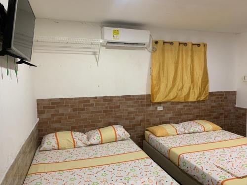 Pokój z dwoma łóżkami i telewizorem w obiekcie Posada Cartagena Histórica w mieście Cartagena de Indias