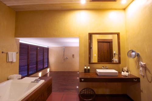 a bathroom with a tub and a sink and a mirror at Jetwing Thalahena Villas in Negombo