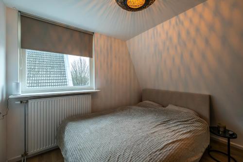 een kleine slaapkamer met een bed en een raam bij Luxe appartement in centrum van Groningen! in Groningen