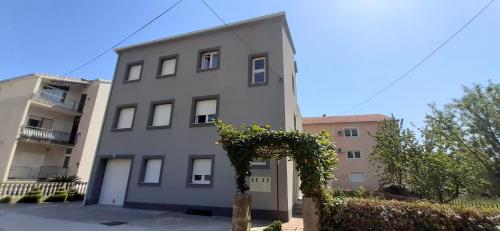 a gray building with a hedge in front of it at Apartment Monika in Kaštela