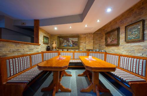 a dining room with two wooden tables and benches at Wellness Vila Astra in Stará Lesná