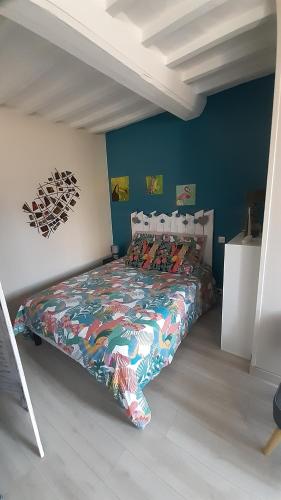 1 dormitorio con 1 cama con un edredón colorido en Studio cosy de Luc, en Luc-sur-Mer