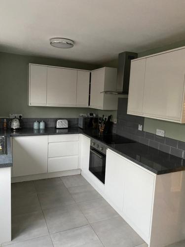 uma cozinha com armários brancos e bancadas pretas em Comfy Darlington Home em Darlington