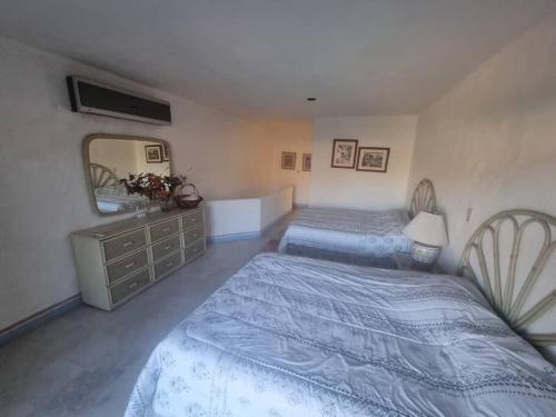 a bedroom with two beds and a dresser and a mirror at Departamento Marinaterra in San Carlos