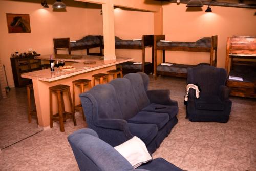 Una sala de estar con un sofá y sillas y un bar. en Hospedaje El Quincho, en Gobernador Gregores