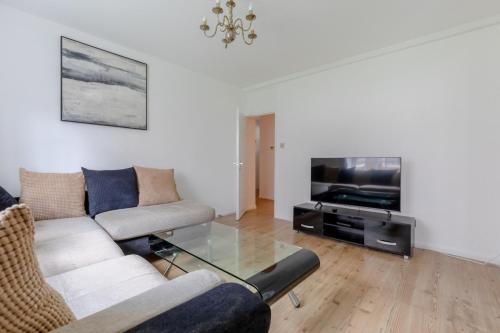een woonkamer met een bank en een tv bij Inviting 2BD Flat 15 Minutes from Regents Park! in Londen