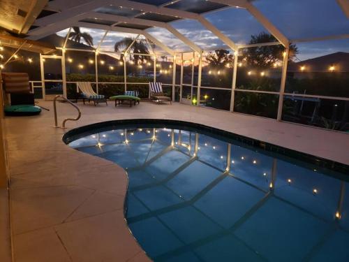 a swimming pool at night with lights at Tropical Breeze Canal Waterfront Home, Heated Pool in Cape Coral